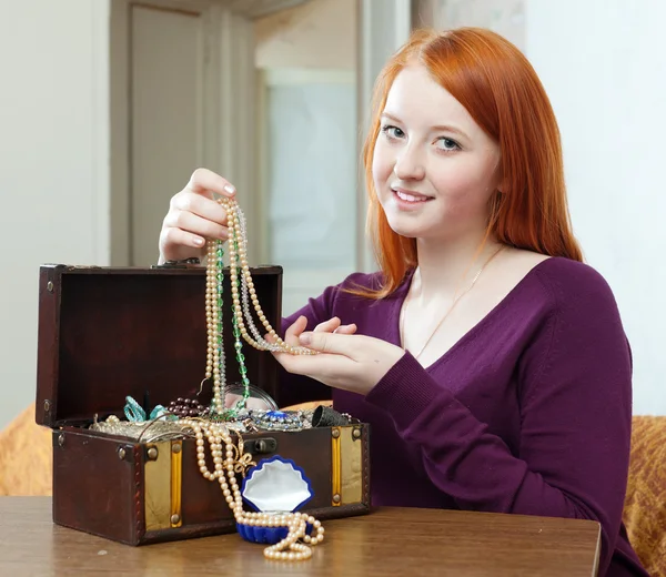 Teenager girl looks jewelry in treasure chest