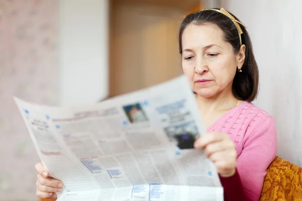 Serious woman reading newspaper