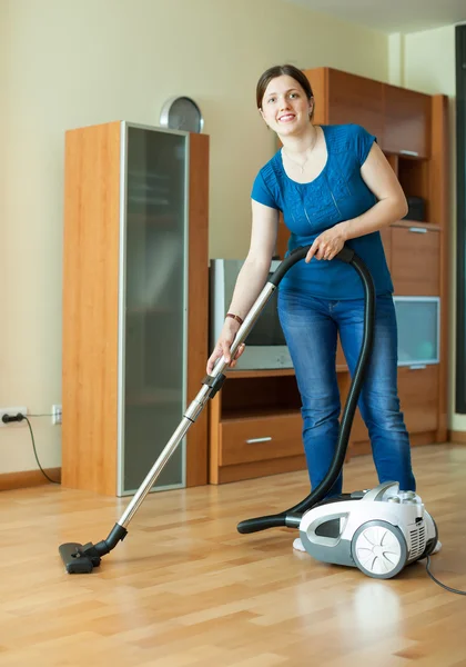 Woman with vacuum cleaner on parquet