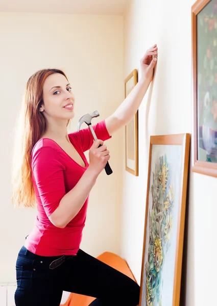 Woman hanging the art pictures on wall