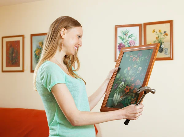 Positive blonde girl hanging pictures