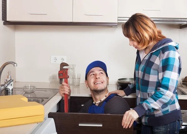 Housewife watching as worker repairing  water lines