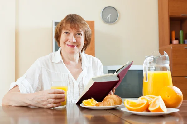 Mature woman with book during breakfast