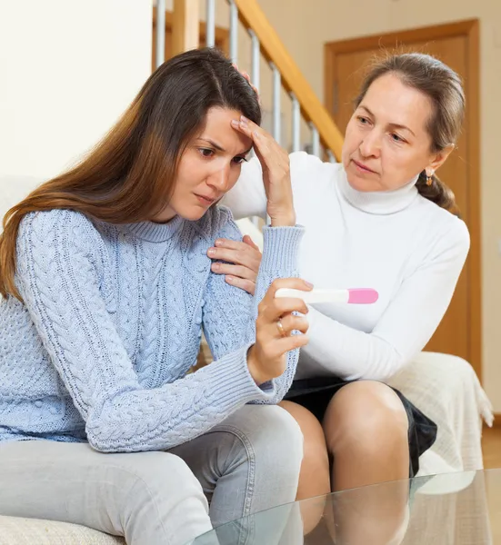 Woman consoling daughter with pregnancy test