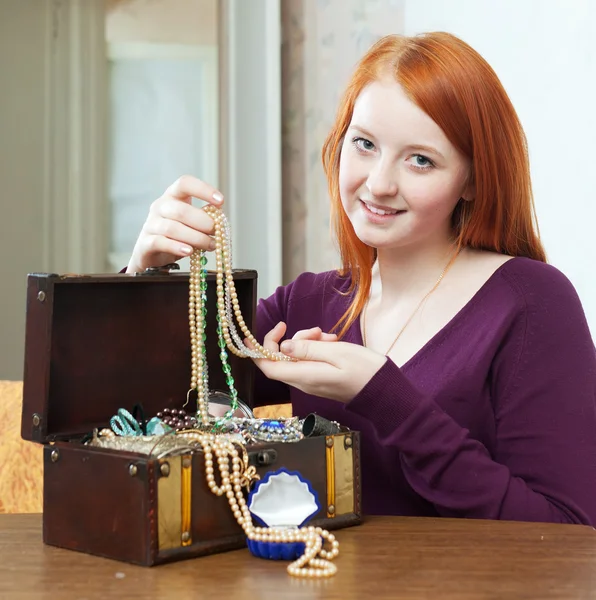 Girl looks jewelry in treasure chest at home