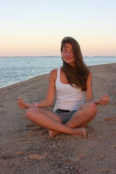 Young woman practicing yoga at the beach