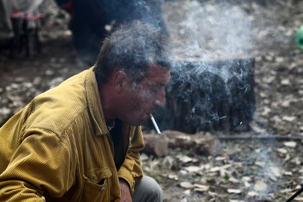 Man lights a cigarette with a burning stick