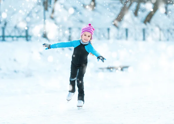 Cheerful little girl in thermal suits skating outdoors
