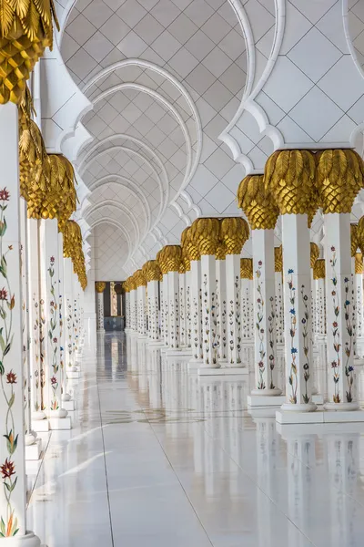 Hallway with golden decorated pillars at the entrance of the world famous landmark Sultan Sheikh Zayed Mosque in Abu Dhabi, UAE