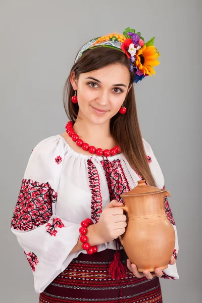 Attractive woman wears Ukrainian is holding a jug national dress