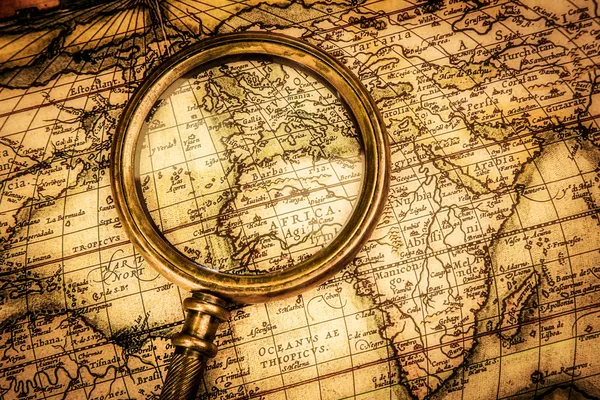 Vintage magnifying glass lies on an ancient world map