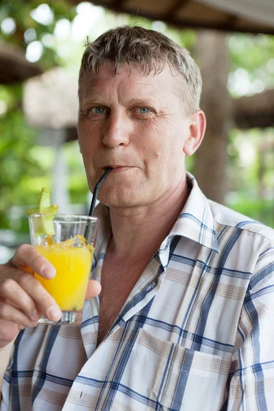 Man drinks orange juice in summer cafe
