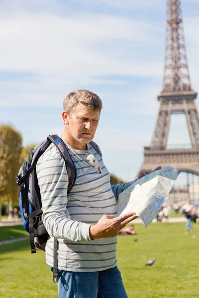 Man with a map of the city in hands against the Eiffel Tower