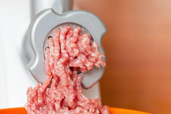 Closeup of minced meat coming out from grinder in shop