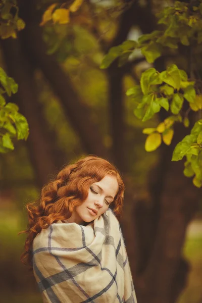 Portrait of young beautiful redhair woman standing in green summer park