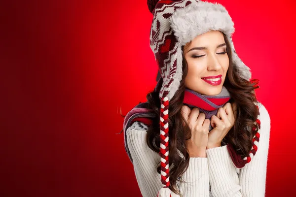 Portrait of girl in winter clothes with bright make-up on a red background