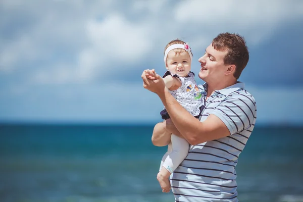 Portrait of a Happy family of man and infant child having fun by the blue sea in summertime