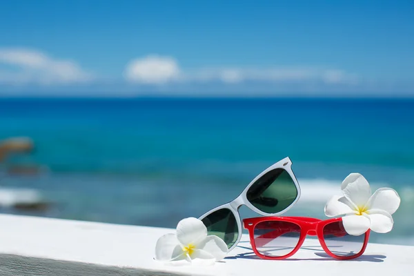 Two pairs of sunglasses on background of ocean