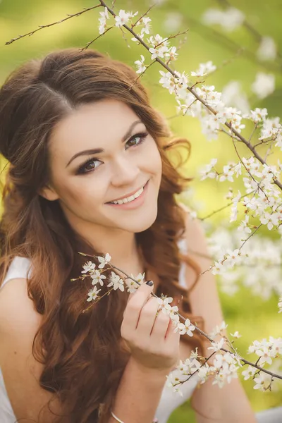 Portrait of young brunette in the spring blooming garden
