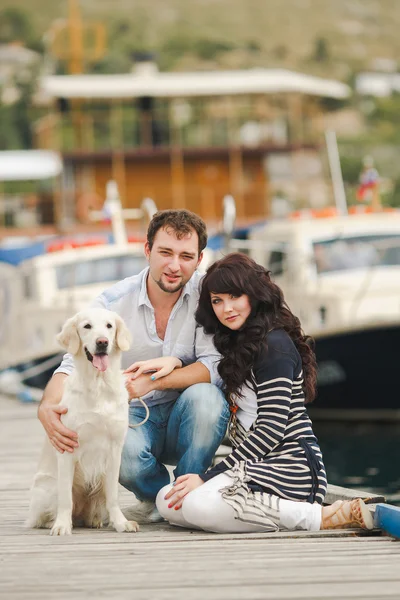 Young couple playing with a dog in the harbor