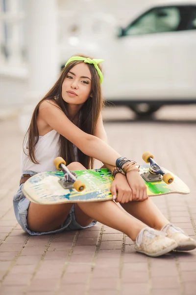 Beautiful and fashionable young woman posing with skateboard