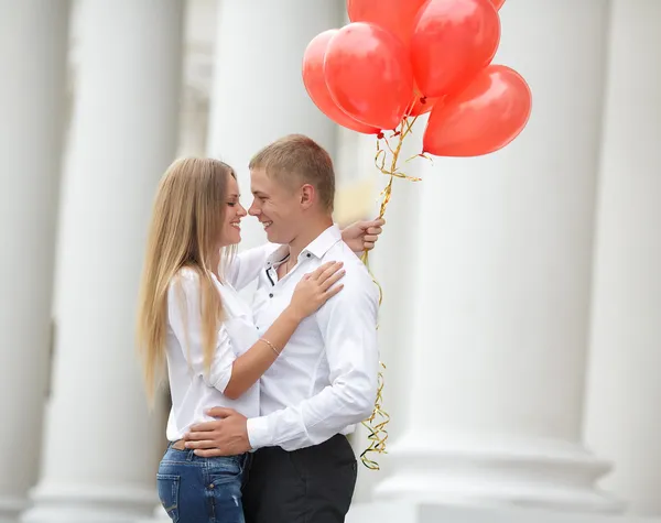 A young couple in love with red balloons on the street