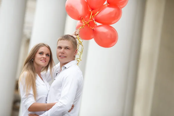 A young couple in love with red balloons on the street