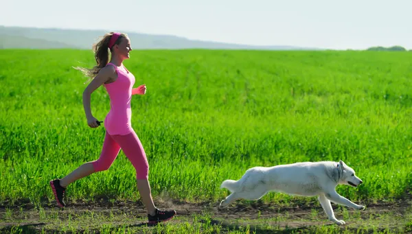 Young attractive sport girl running with dog in park