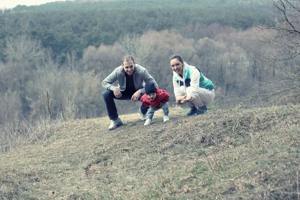 Beautiful young sporty family stands back on the mountain