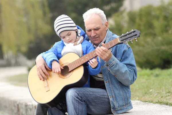 Grandfather and grandson playing guitar