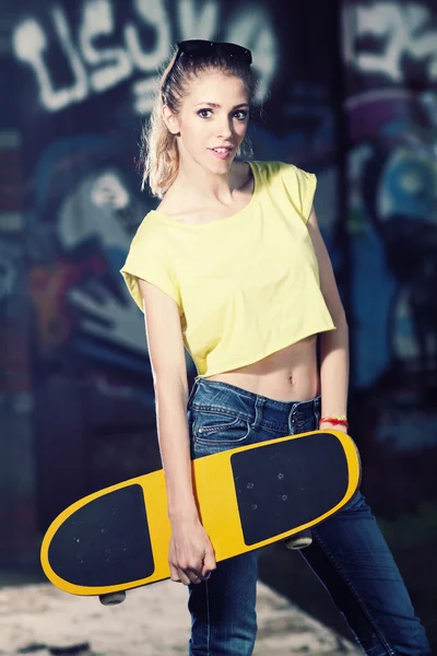 Cute slim girl posing with skateboard