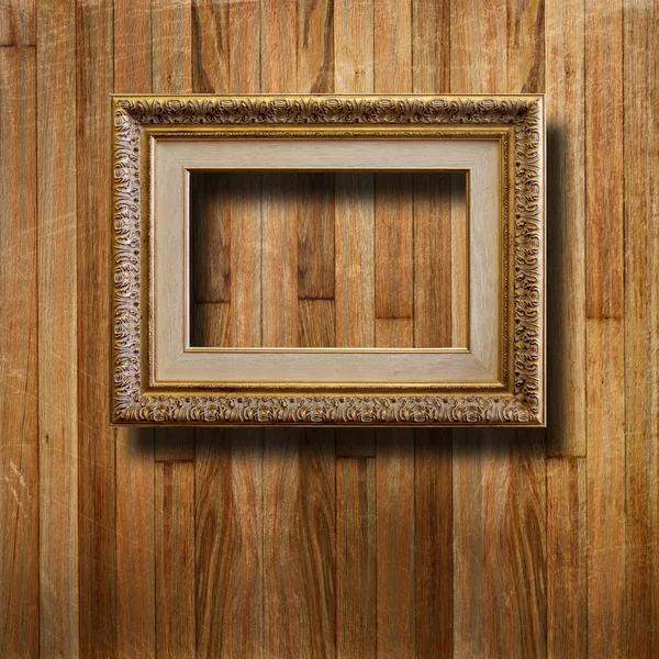 Old gilded picture frame for portrait on the scratched wooden wa