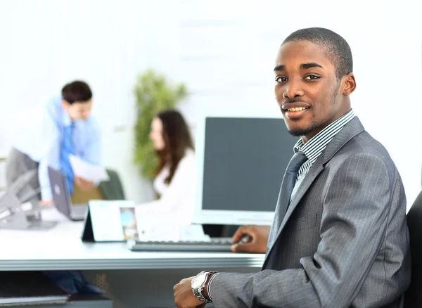 Portrait of smiling African American business man with executives working in background