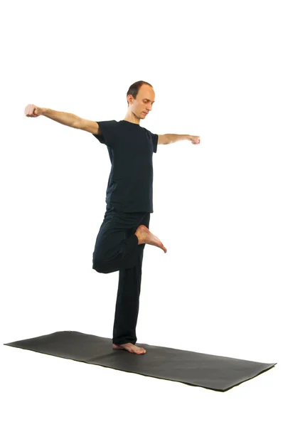 Tall man doing Vrikshasana yoga position