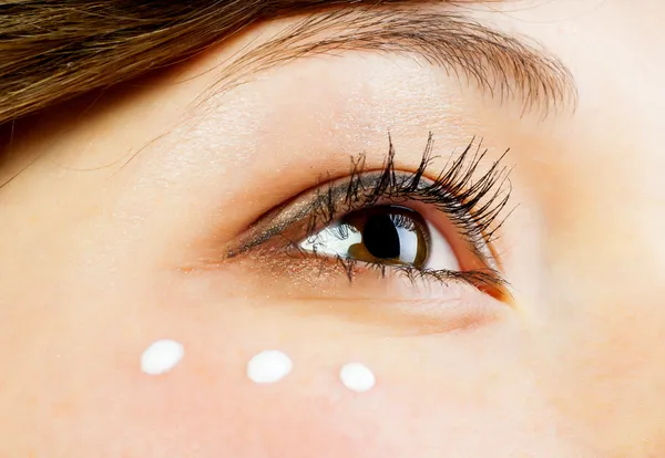 Facial cream under woman's eye