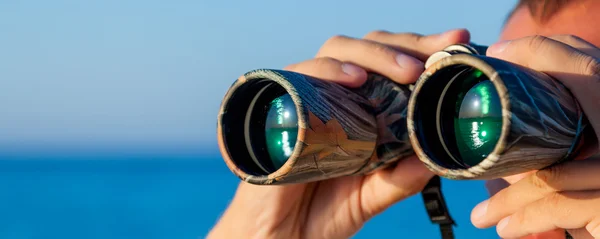 A man is looking to the binocular