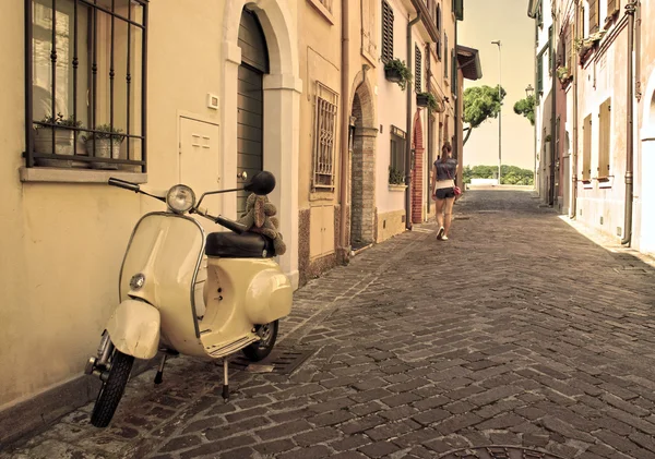 Vintage scooter parked in a typical narrow old street in Rimini, Italy