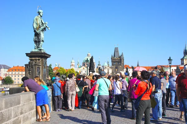Statue of St.John of Nepomuk on Charles Bridge. Crowds of tourists are going to make a wish to the monument, which according to legend, brings good luck on September 5,2013 in Prague
