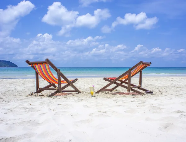 Two beach chairs on the white sand beach before blue sea on a beautiful tropical beach