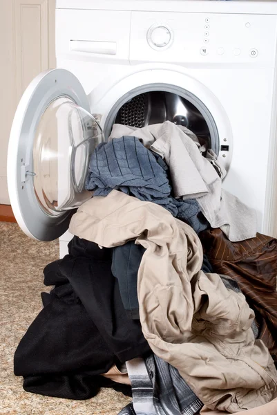 A washing machine and a big pile of laundry