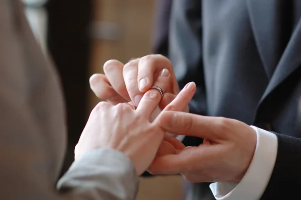 Groom putting a ring on bride\'s finger