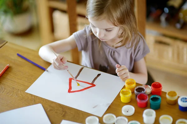 Cute girl is drawing with paints in preschool