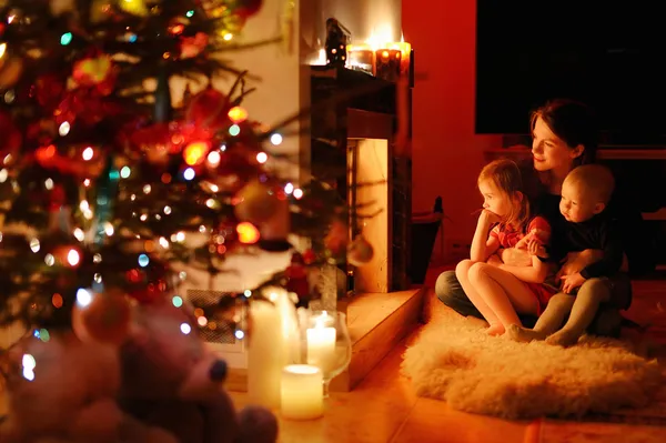 Young mother and her daughters by a fireplace