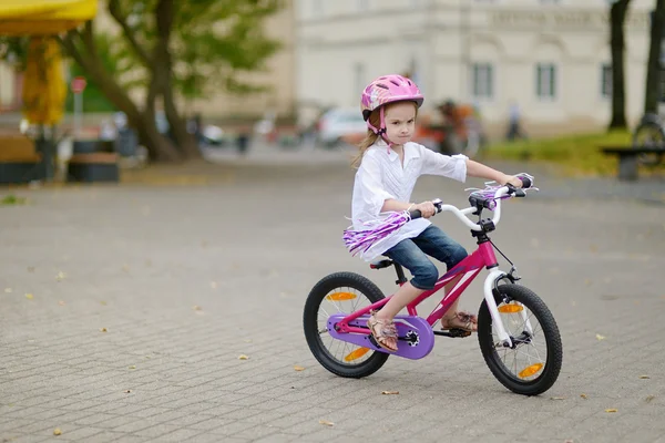 Little girl riding a bike in a city