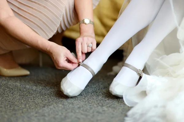 Helping a bride to put her wedding shoes on