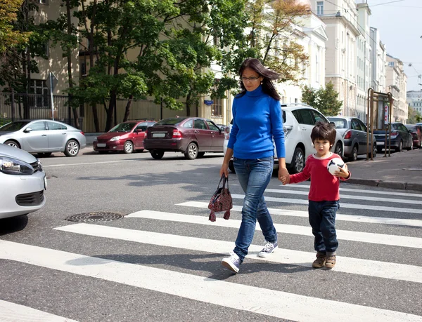 Mother and son are on a pedestrian crossing in the city