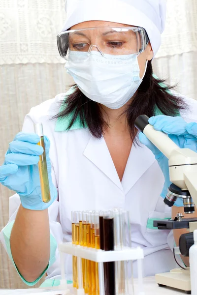Doctor looking at a test tube of yellow solution