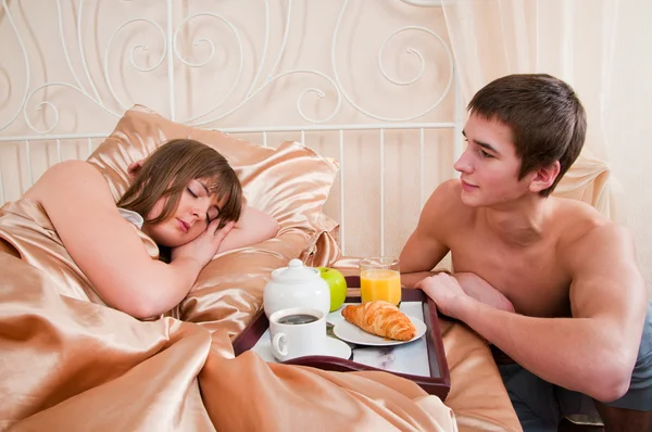 Happy man and woman having luxury hotel breakfast in bed togethe