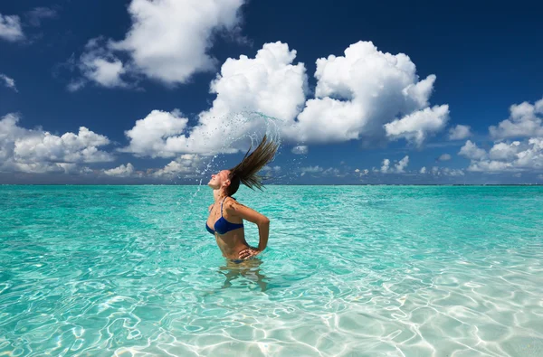 Woman splashing water with hair in the ocean