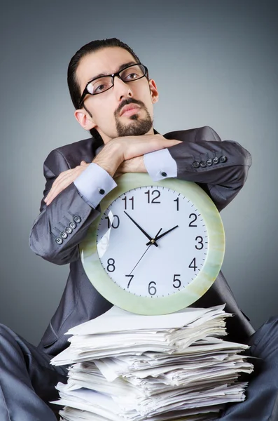 Man with clock and pile of papers